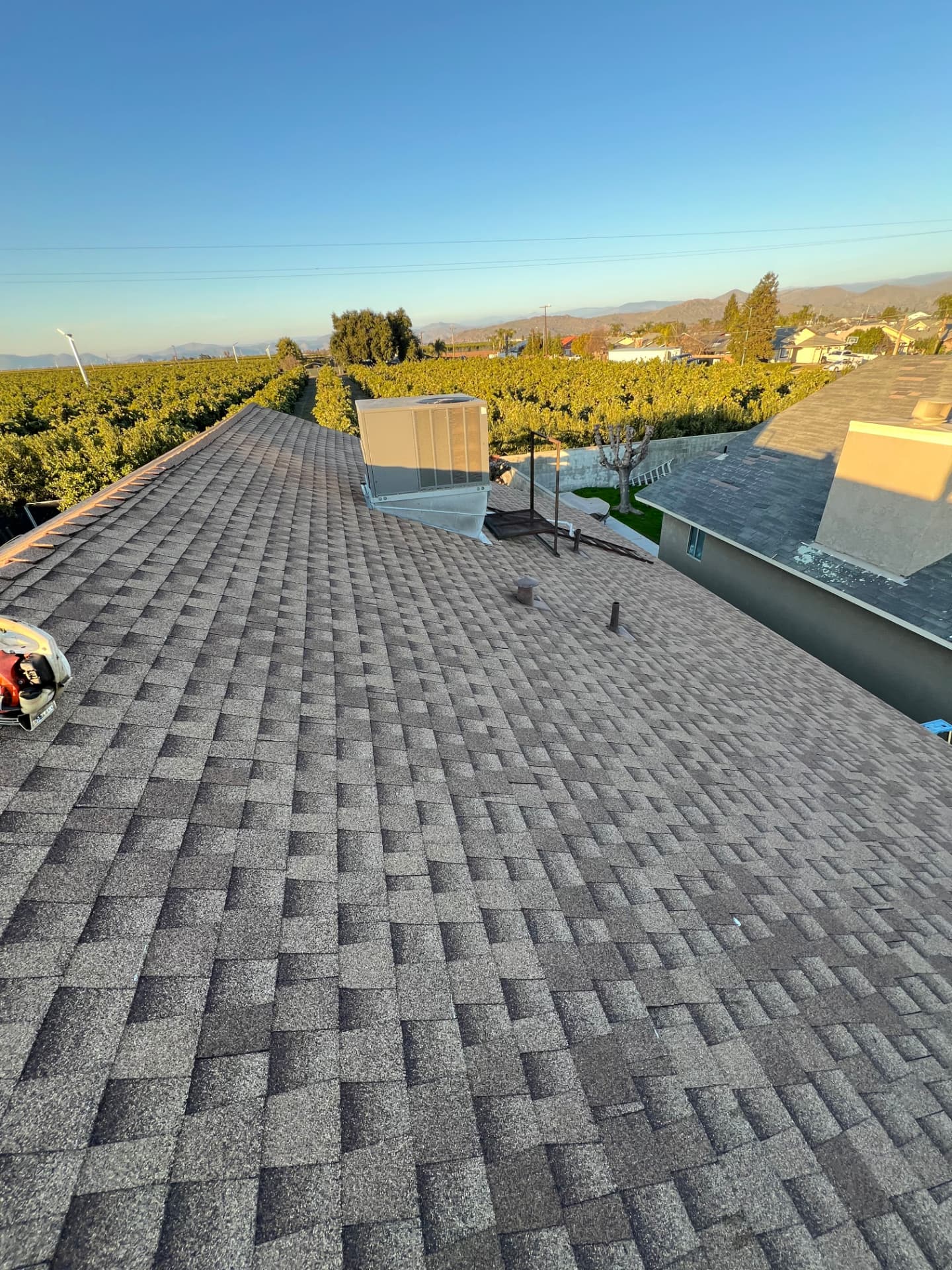 Completed architectural shingle roof with rooftop unit and Central Valley view