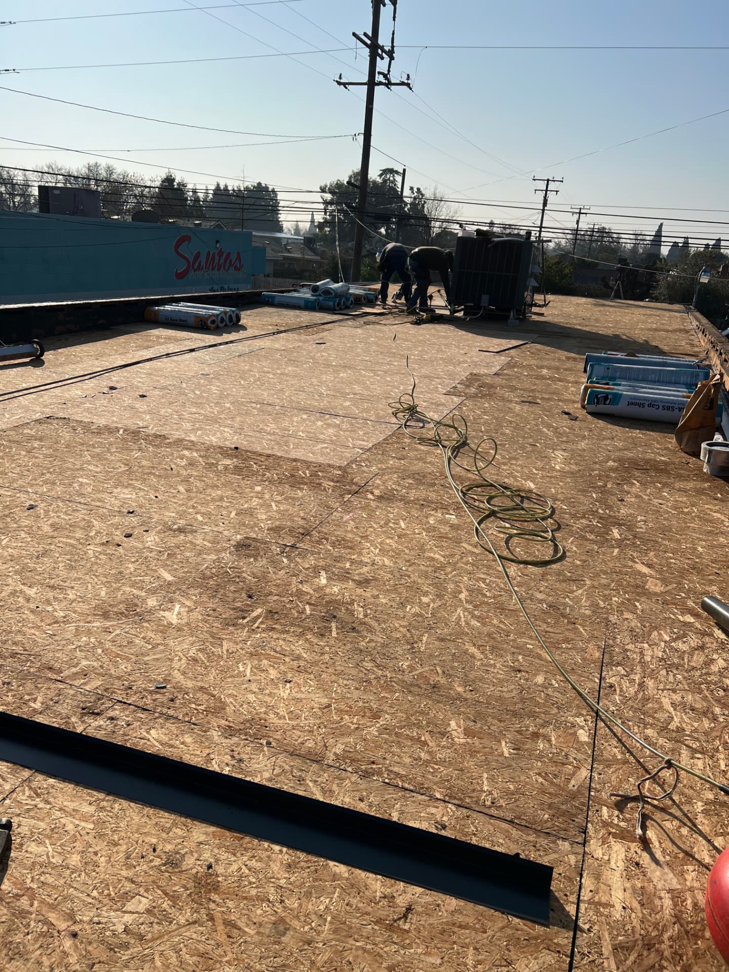 Commercial roof deck prep with crew and roofing materials on site