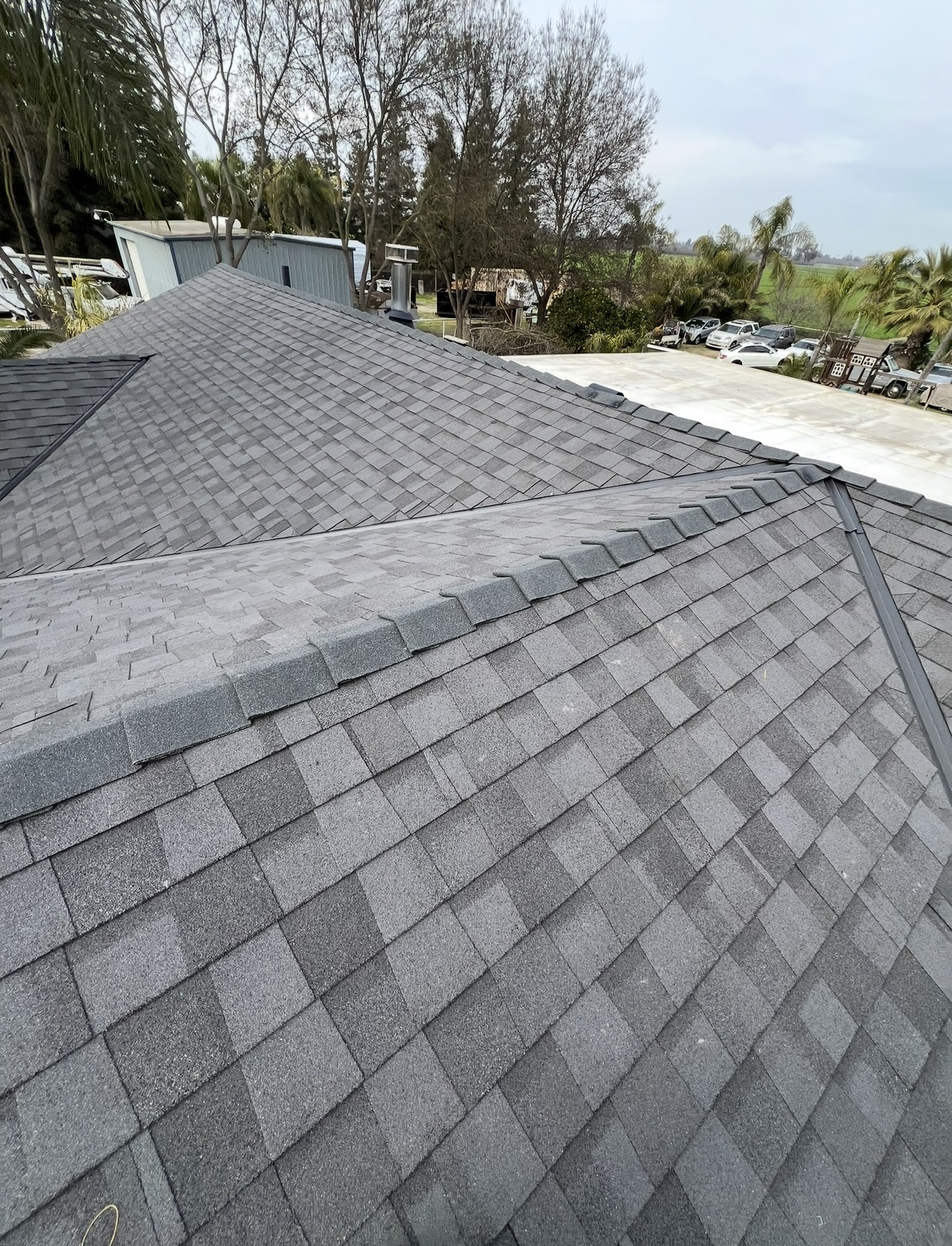 Newly completed gray shingle roof with clean ridge caps