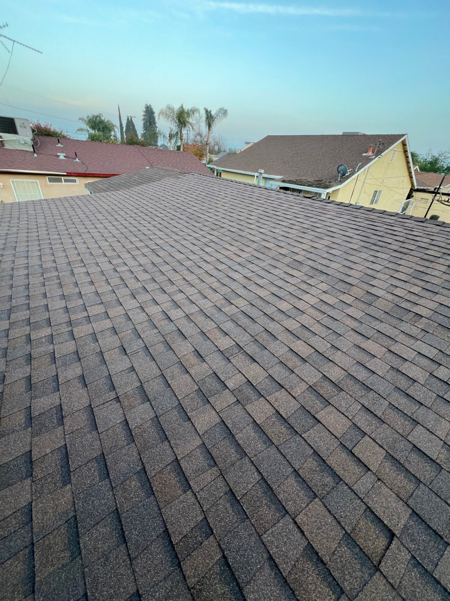 New gray shingle roof with neat ridge caps in a residential neighborhood