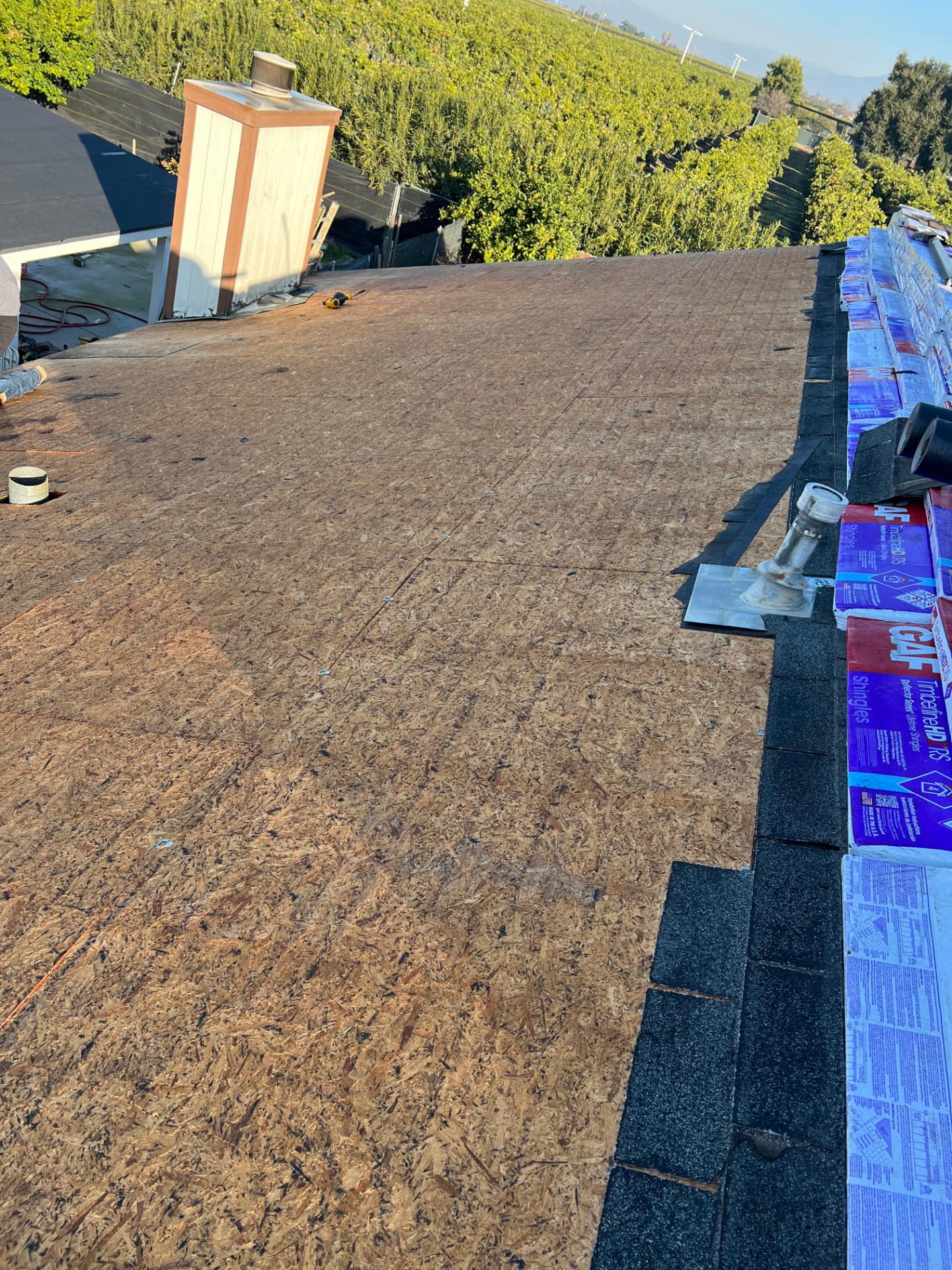 Residential roof deck exposed during tear-off with shingle bundles ready