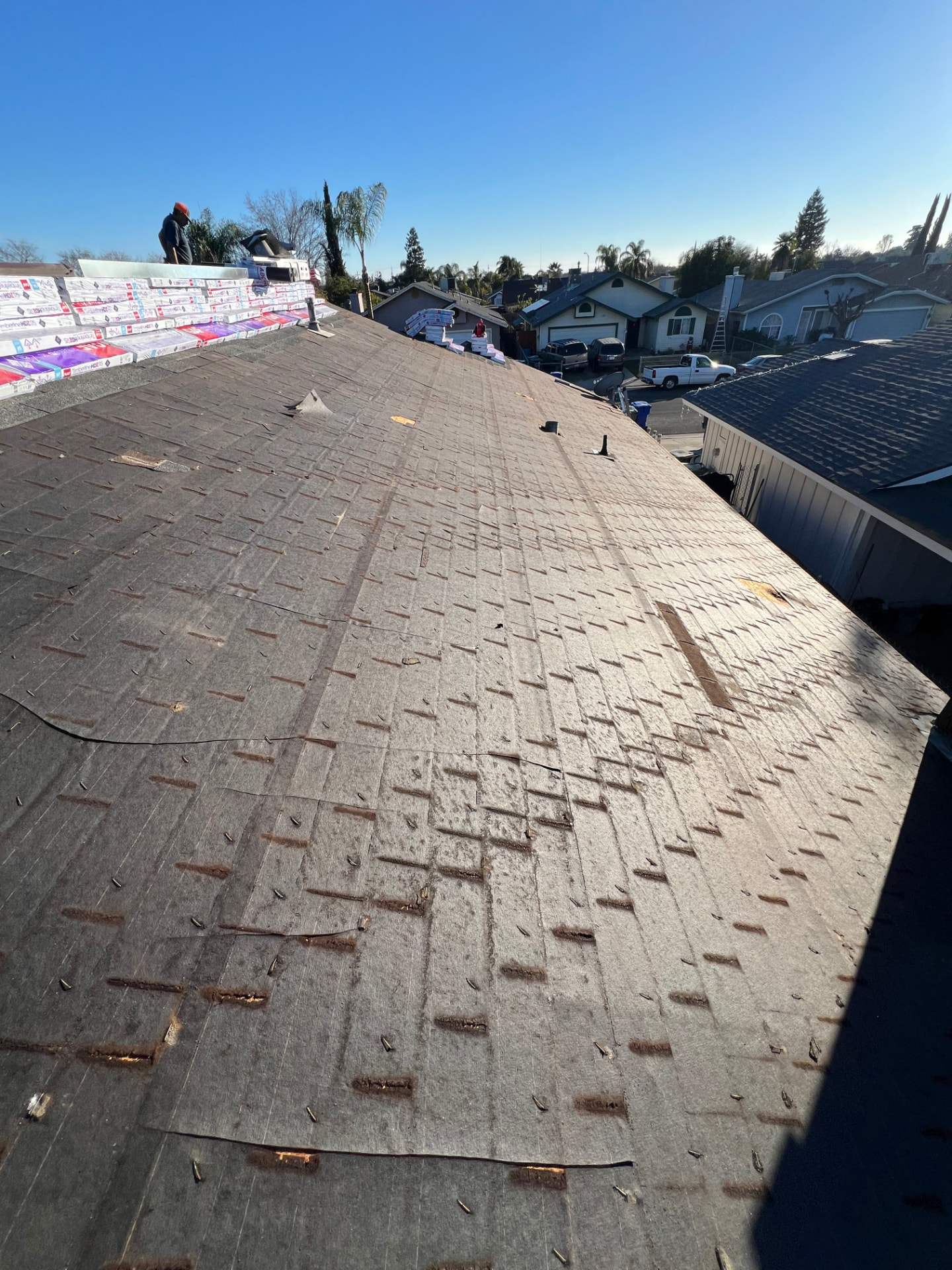 Residential tear-off in progress with new shingle bundles stocked on the ridge