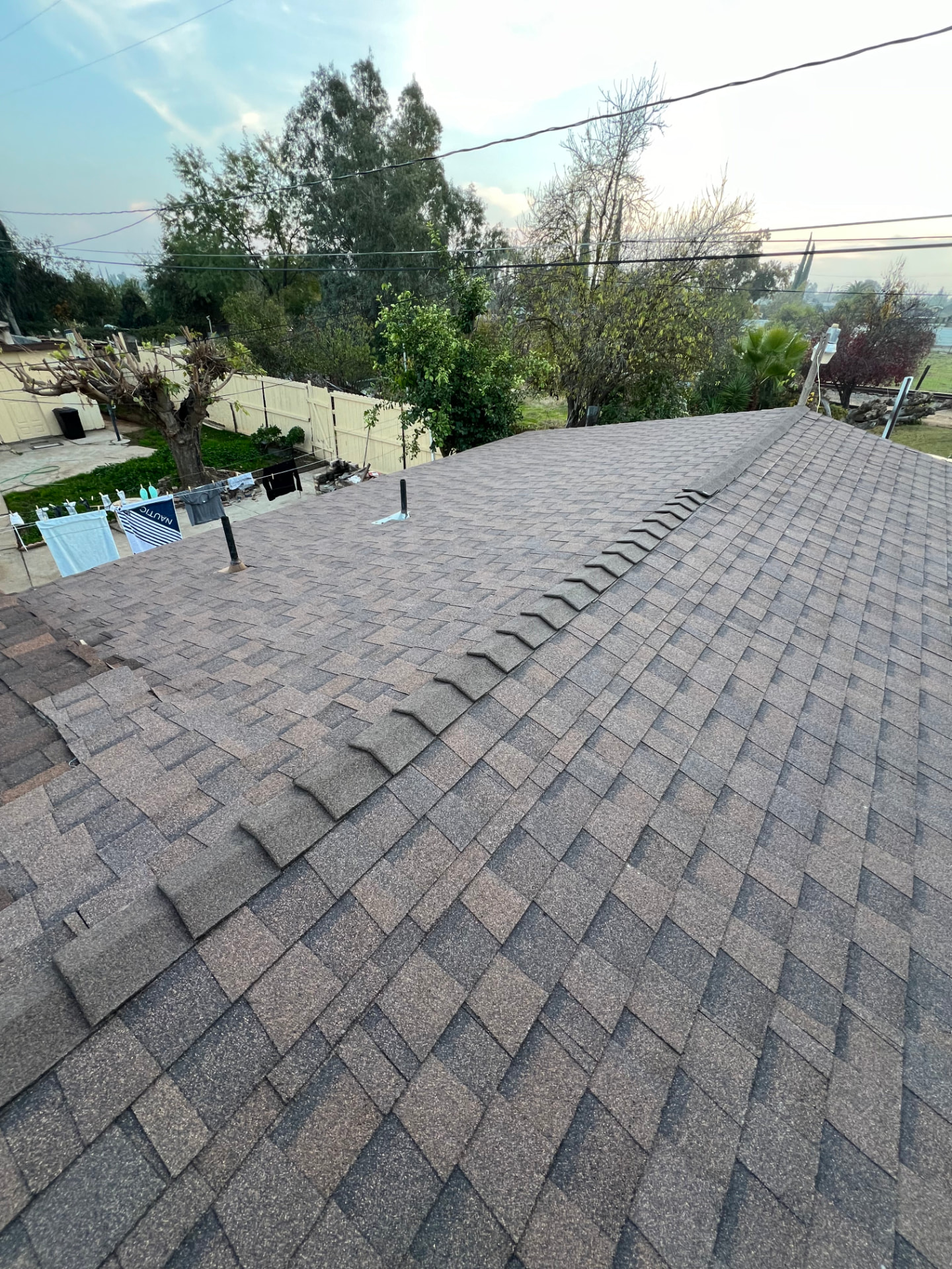 Completed architectural shingle roof with clean ridge caps at dusk