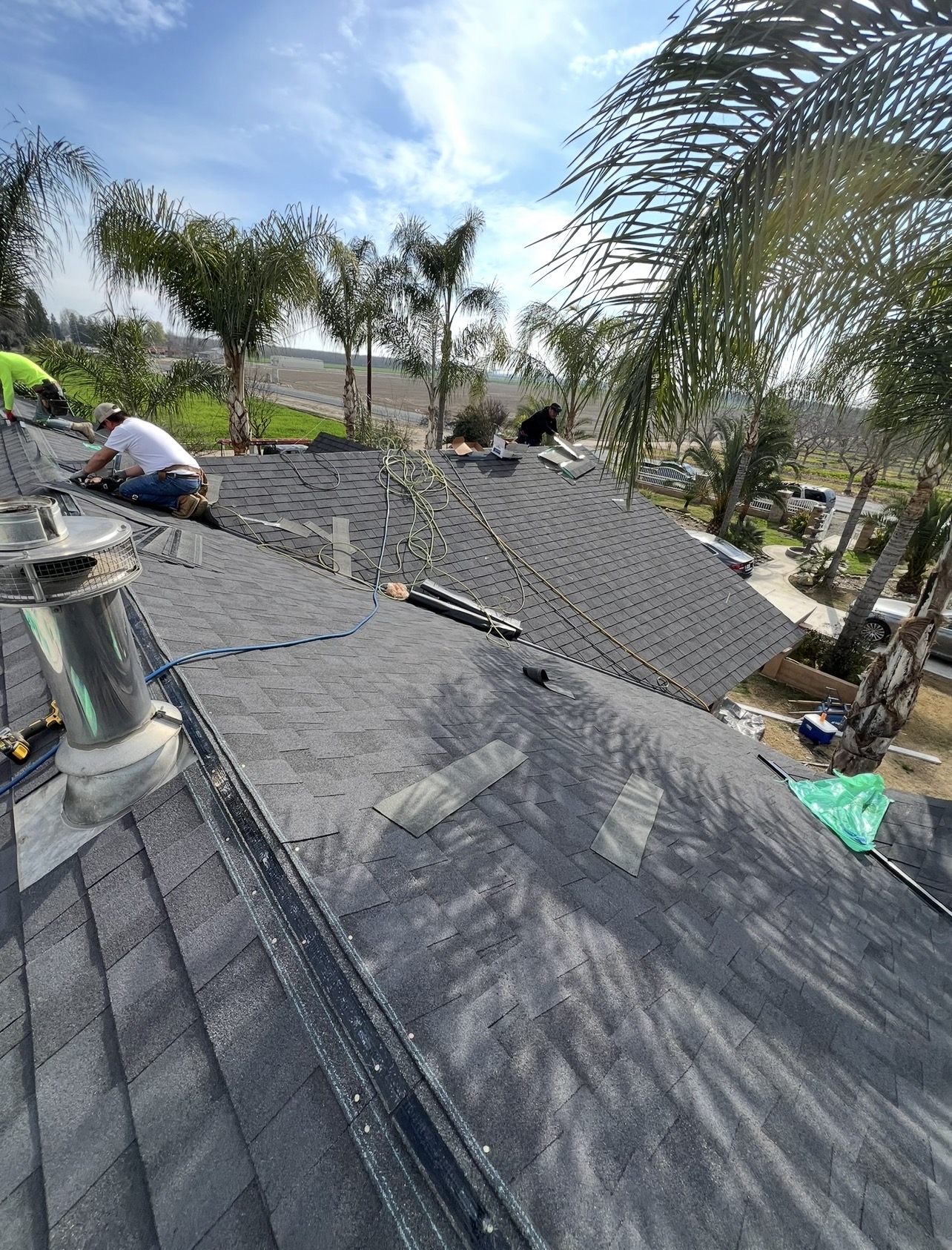 Crew installing architectural shingles around a chimney