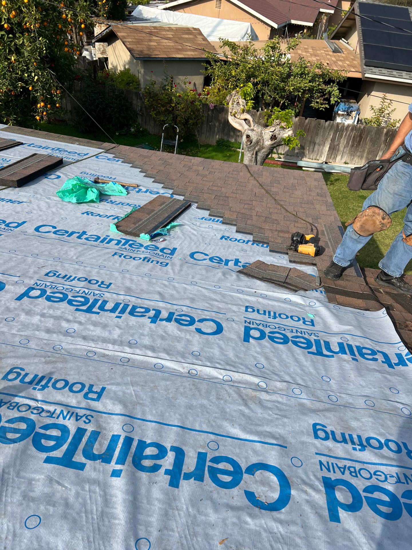 Crew installing brown architectural shingles over CertainTeed underlayment