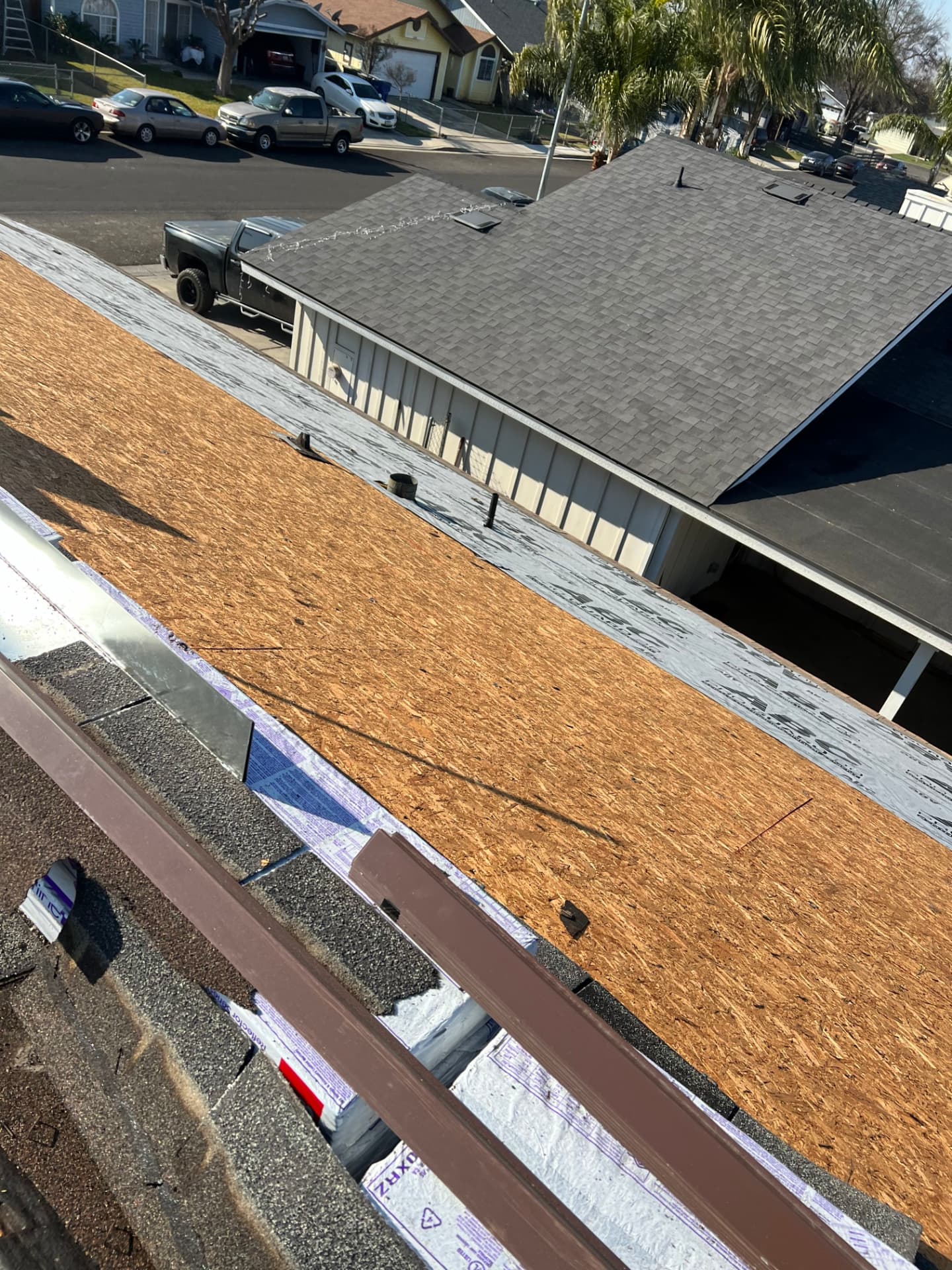 Residential roof tear-off with exposed underlayment in a neighborhood