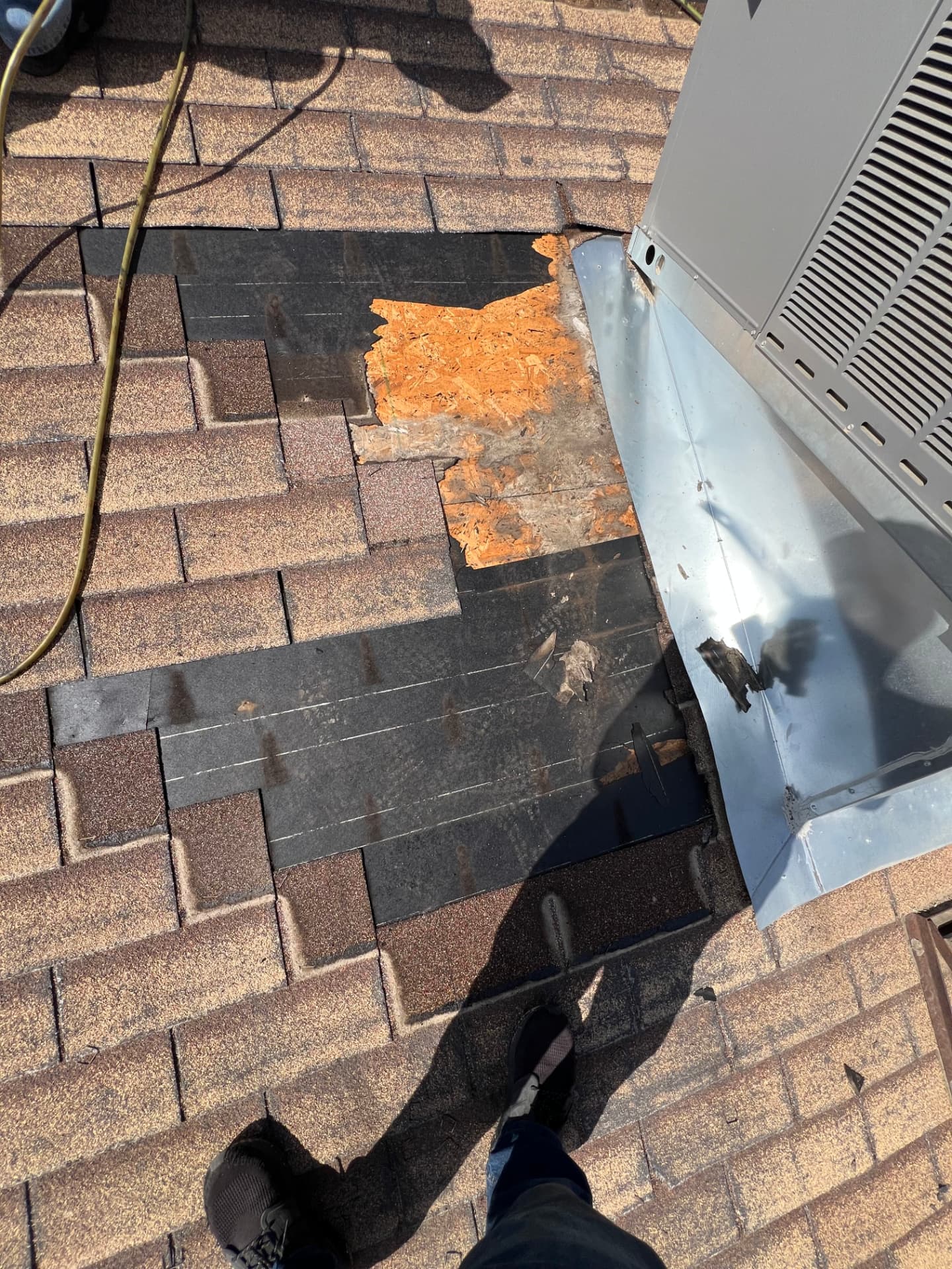 Damaged shingle repair around an HVAC unit with exposed deck